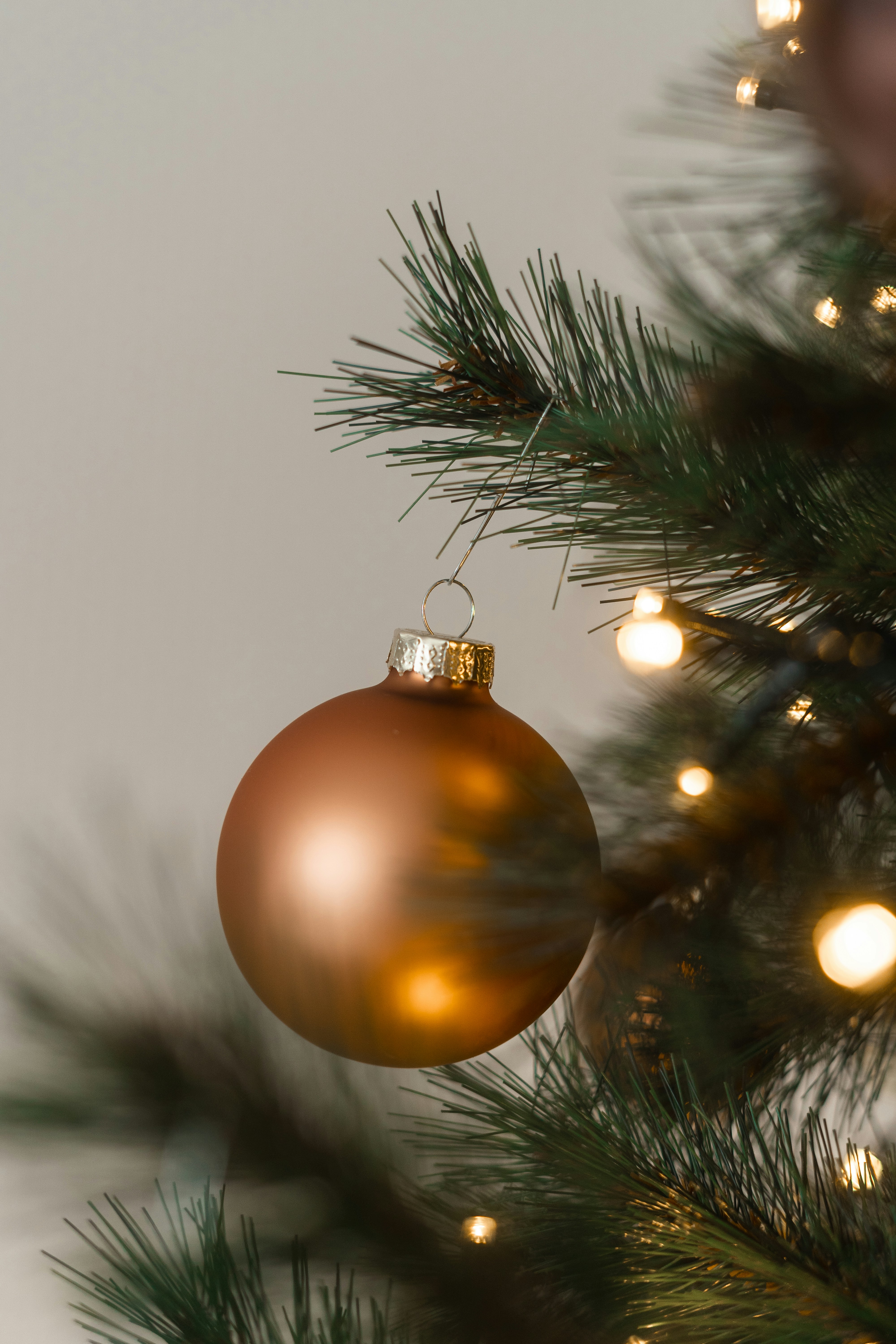 A bronze christmas ornament hangs on a tree.