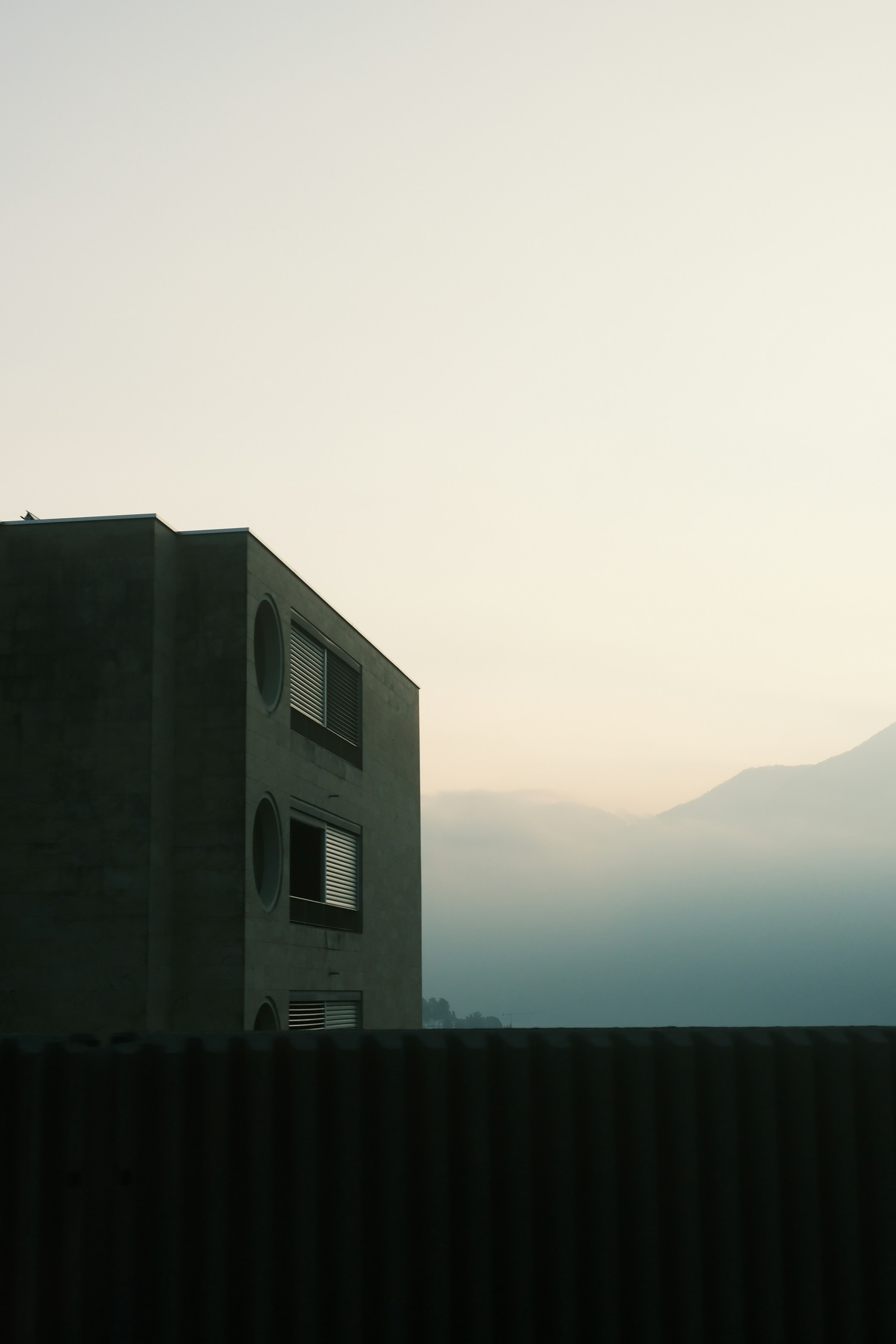 Modern building against misty mountains at dawn