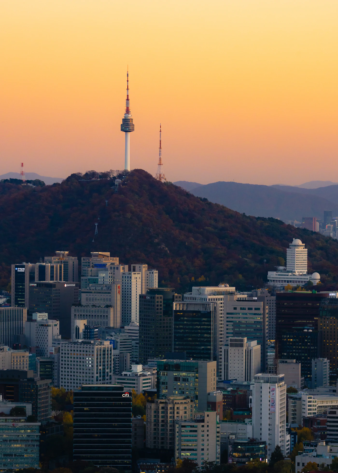 The Seoul city skyline with a tower on a hill at sunset