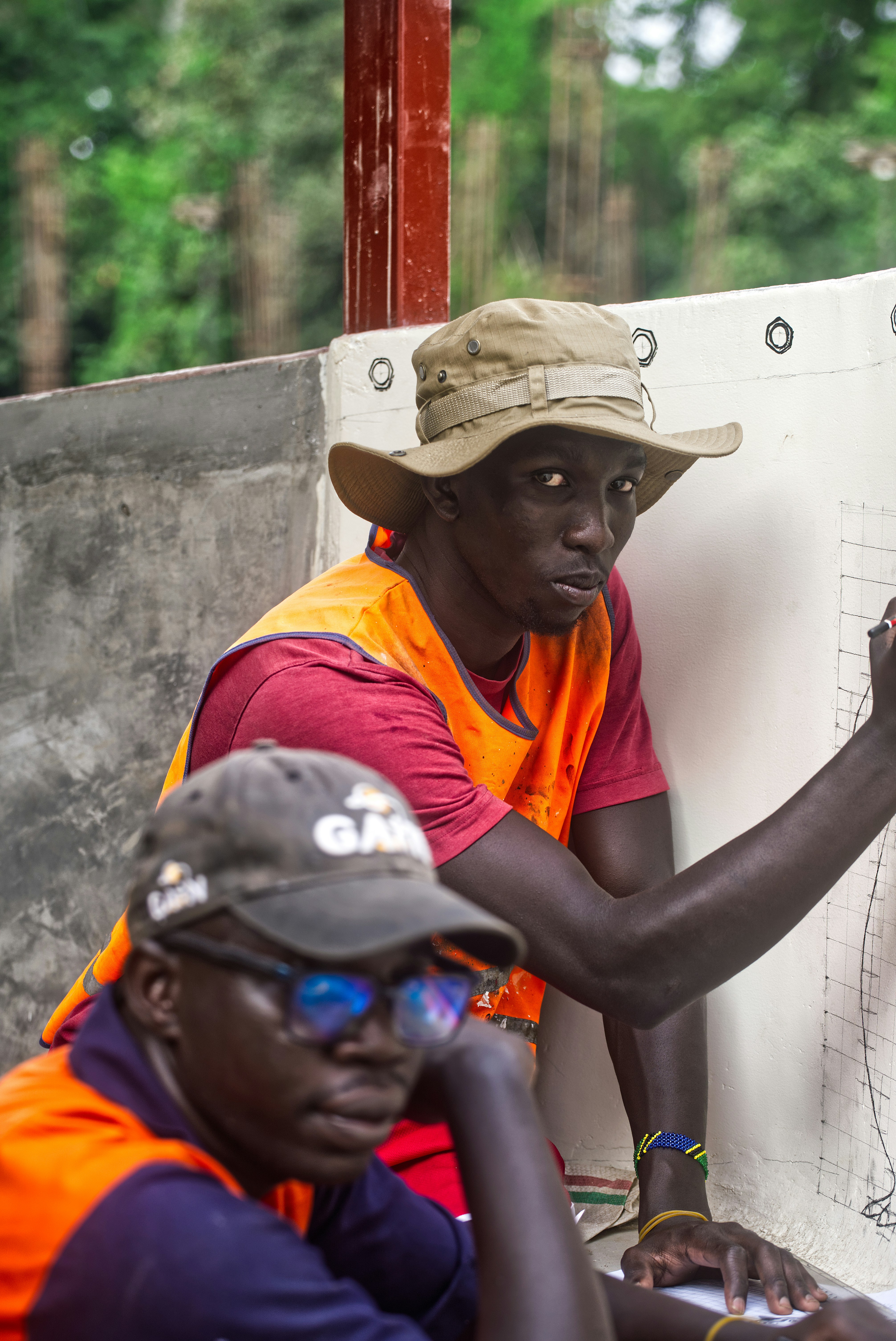 Two men in hats and vests looking at a map.