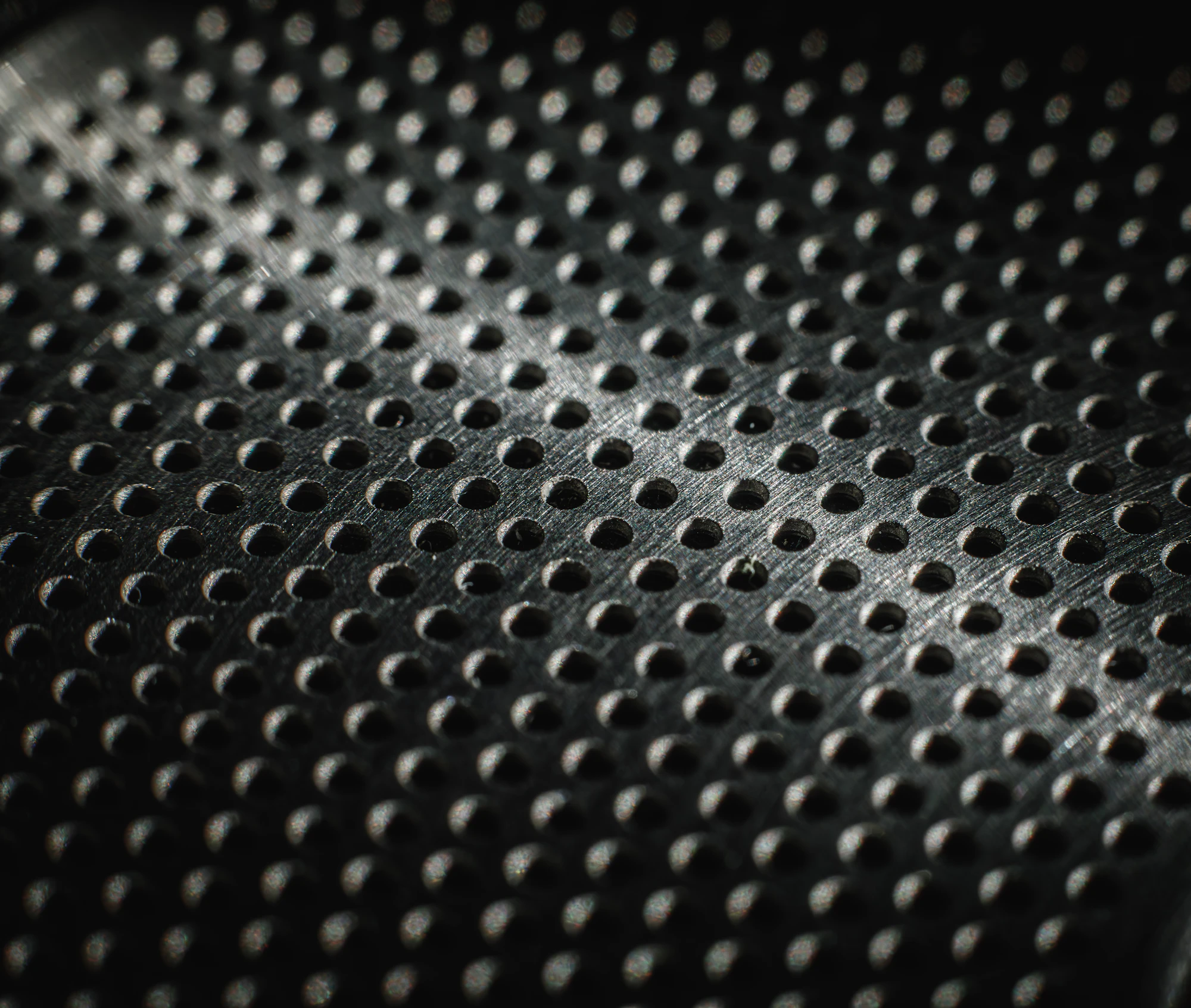 Uniform matte perforated metal texture evoking bead-blasted finishes