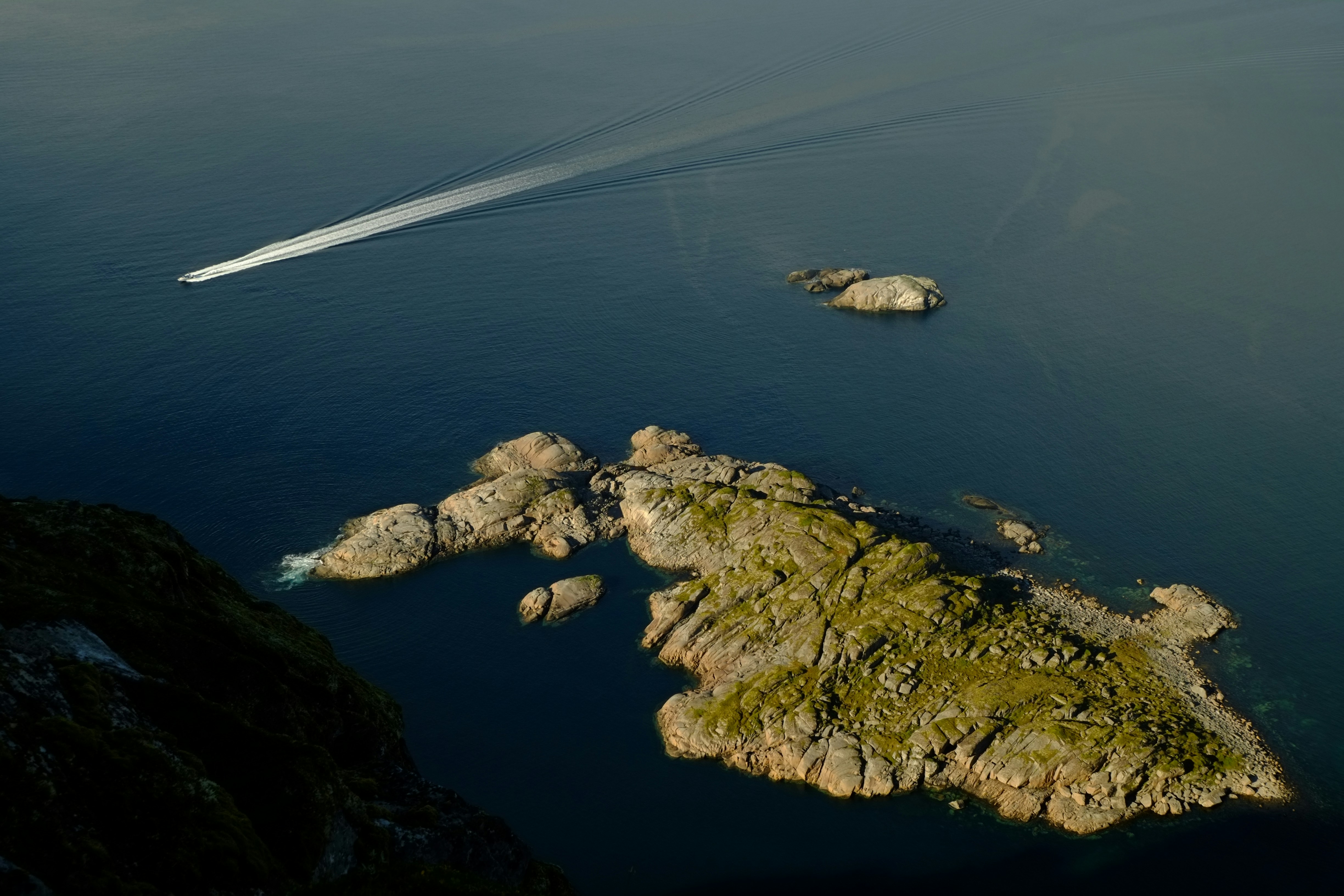 Bateau laissant une traînée blanche près des îles rocheuses