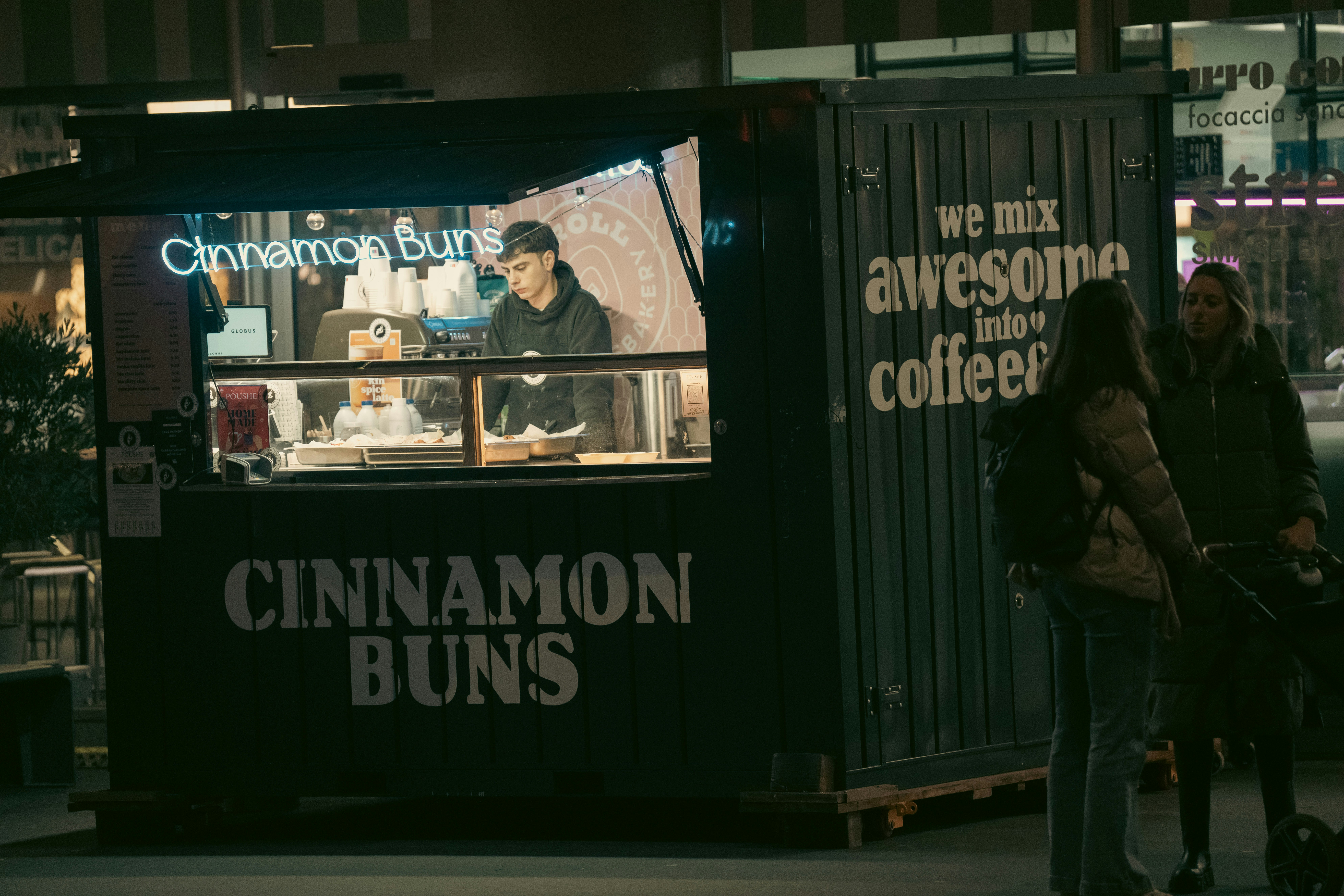 People at a cinnamon bun stand at night.