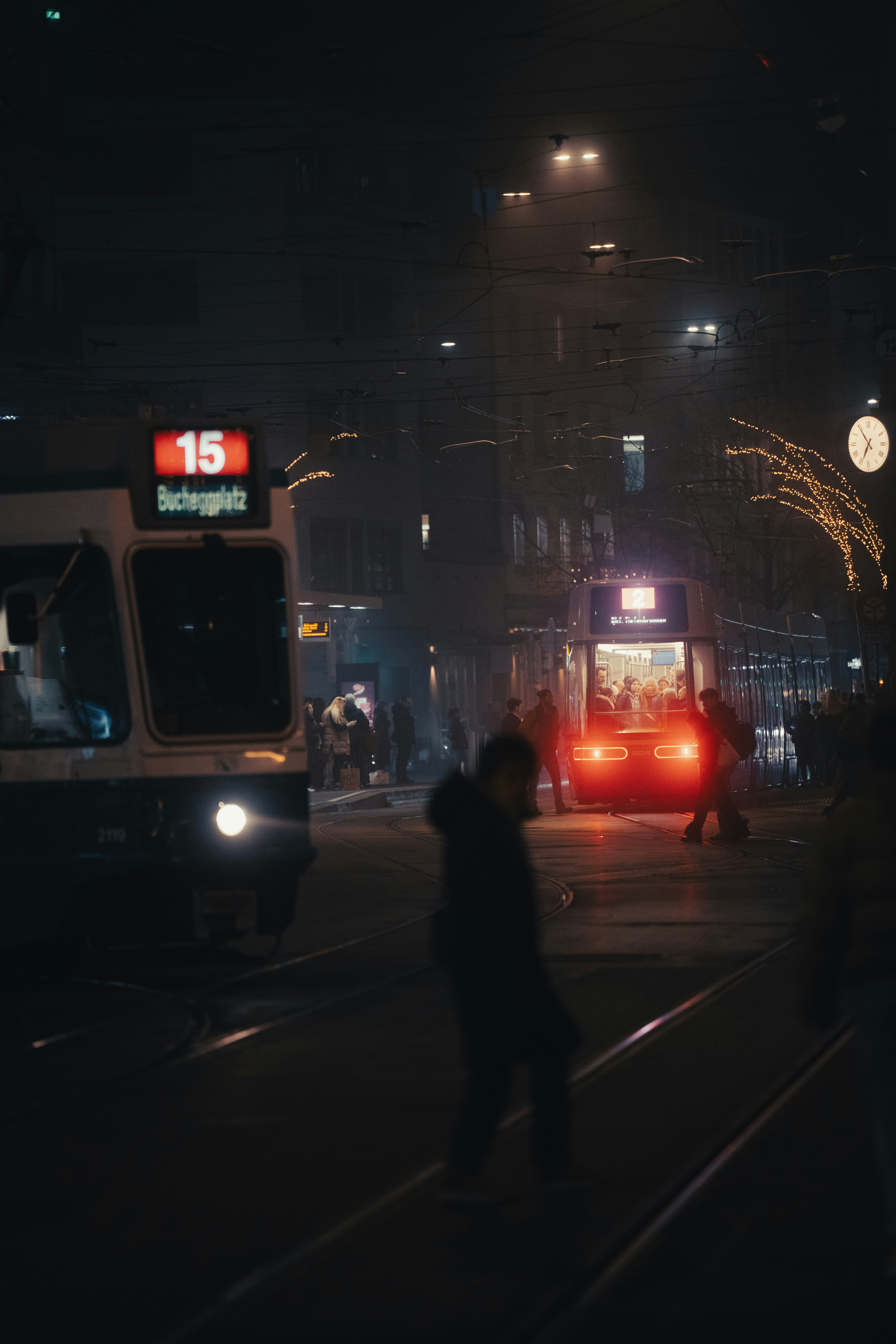 Trams at a busy city street at night.