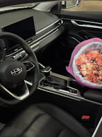 A bouquet of flowers sits on a car's center console.