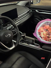 A bouquet of flowers sits on a car's center console.