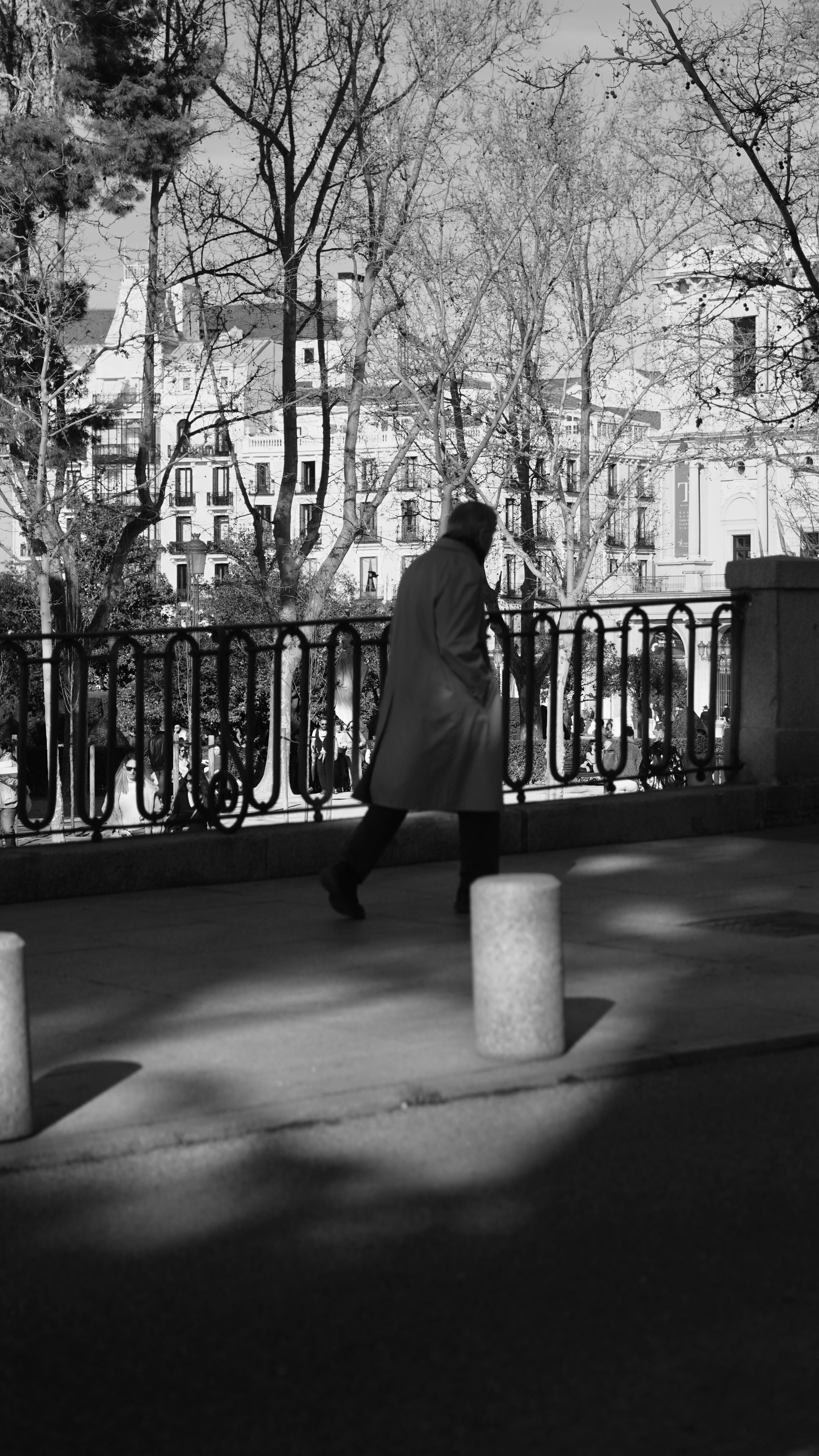 Man walking past ornate railing with buildings behind