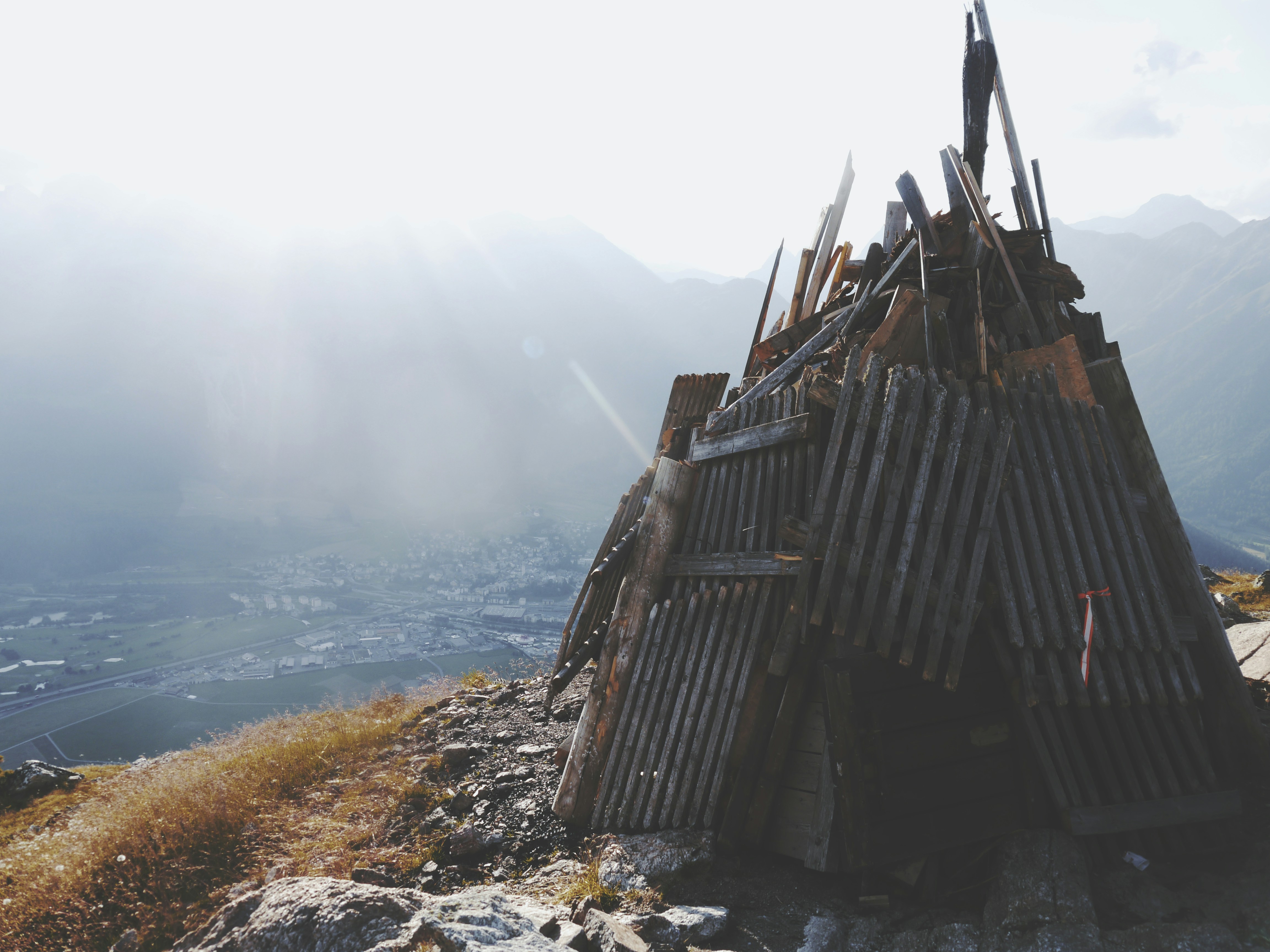 Dilapidated wooden structure on a mountain overlooking a valley.