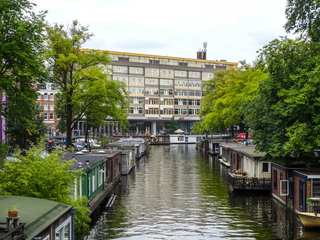 Houseboats line a canal with trees and buildings.