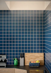 Modern kitchen counter with blue tiled backsplash and fruit.
