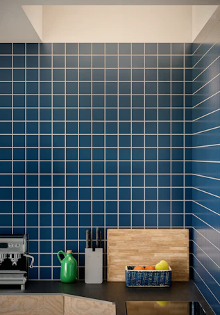Modern kitchen counter with blue tiled backsplash and fruit.
