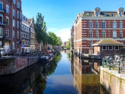 Canal lined with buildings and trees under a clear sky.