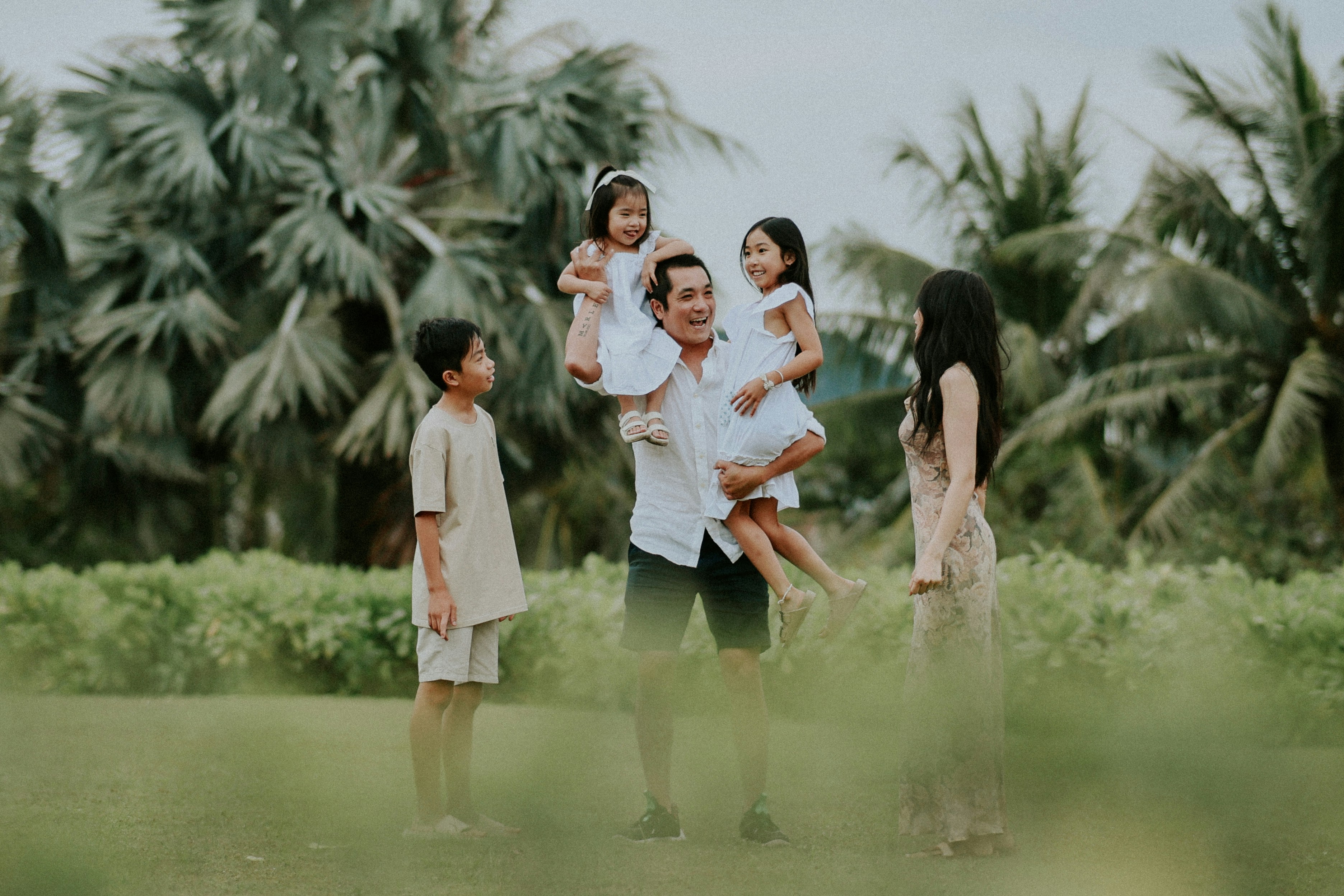 Family enjoying time together outdoors with palm trees.