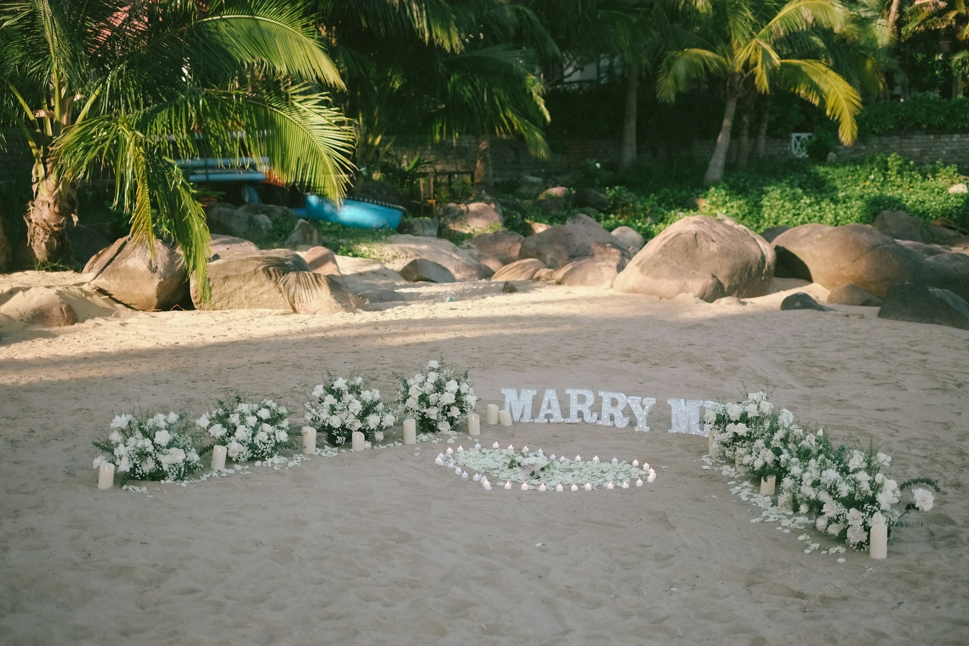 Marry me sign on a sandy beach with flowers