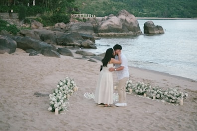 Couple kissing on a beach during a wedding ceremony.