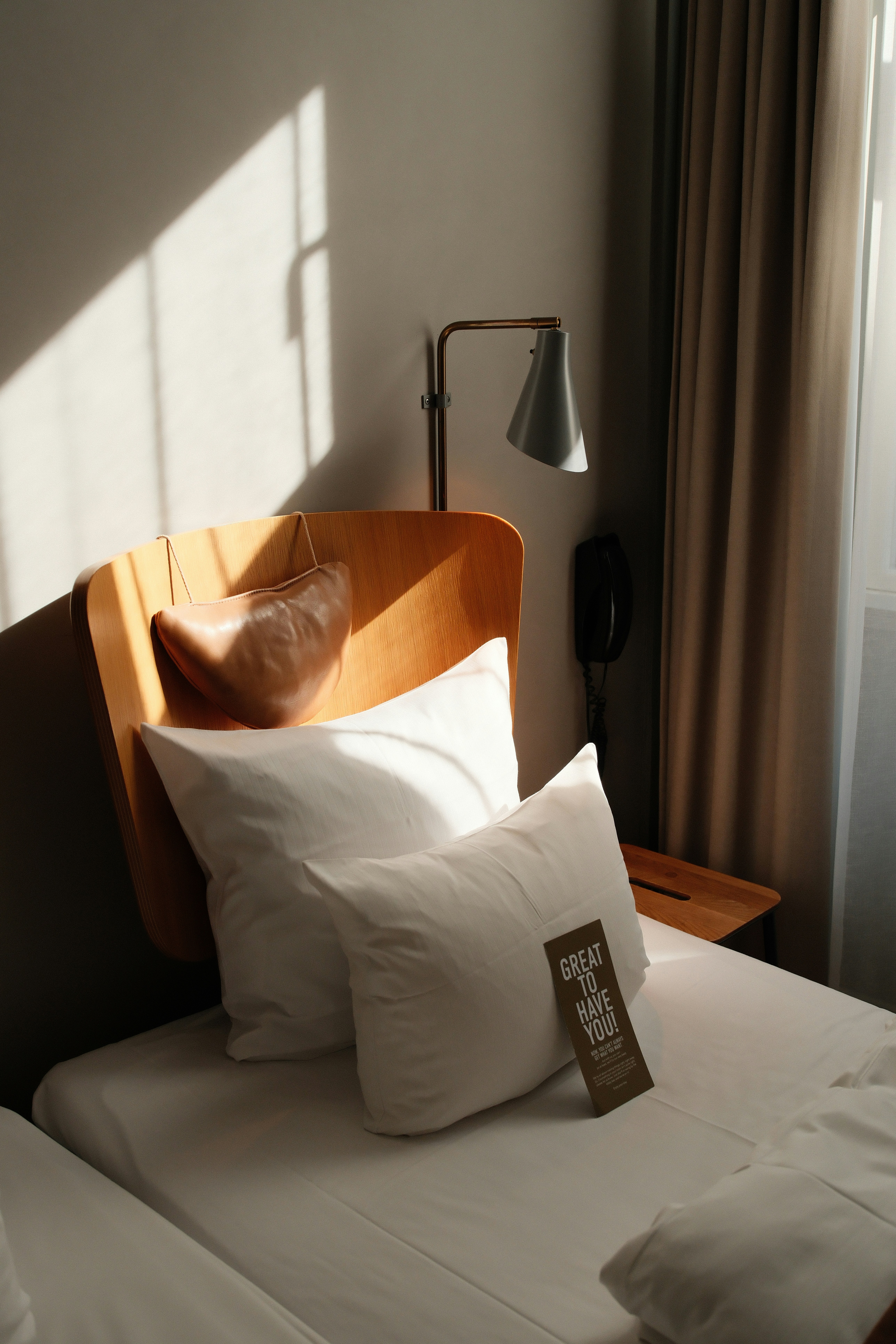 A neatly made hotel bed with pillows and lamp.
