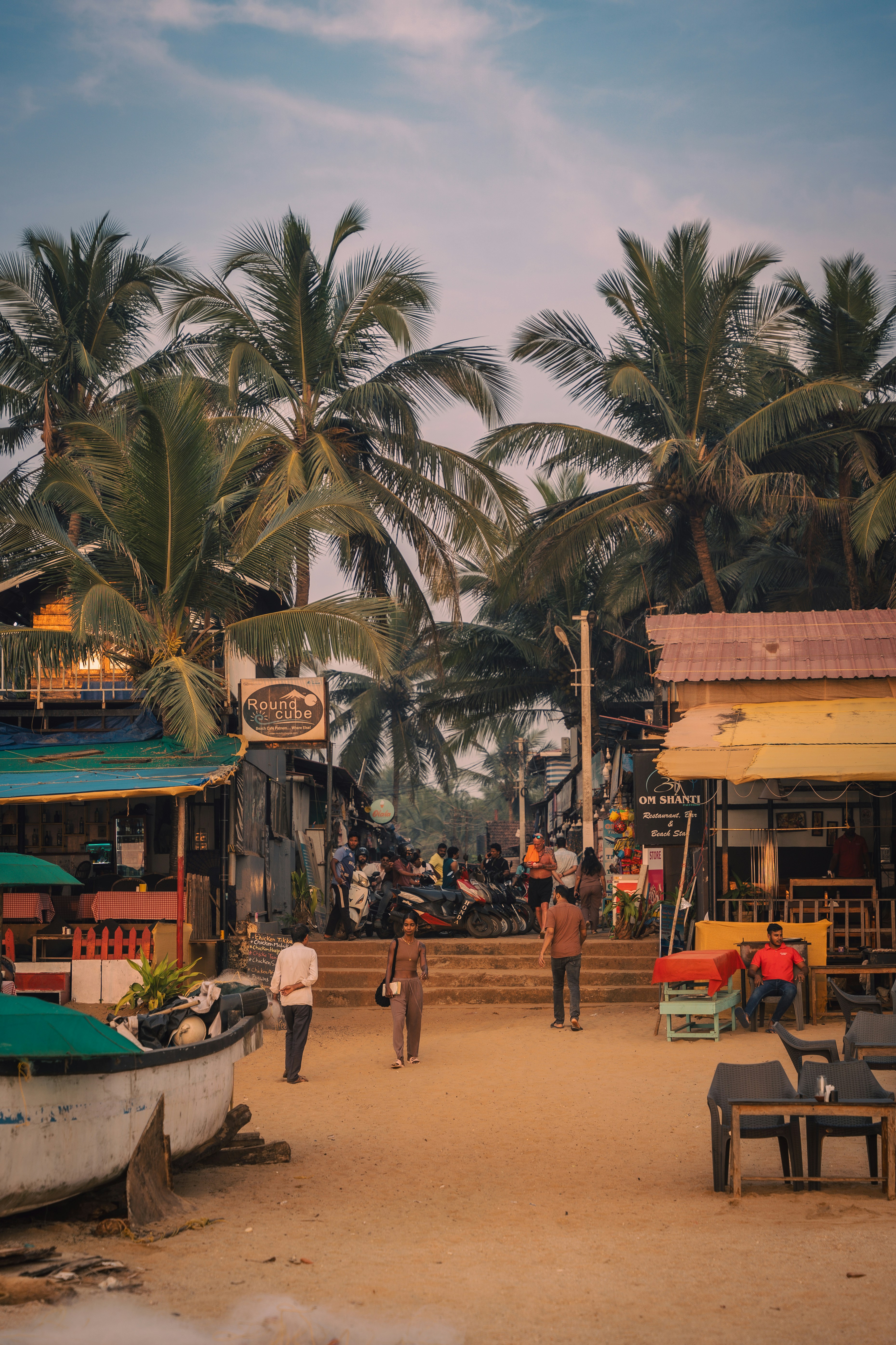 Tropical beach street lined with palm trees and stalls.