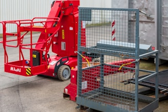 Red articulated boom lift with basket and metal cage