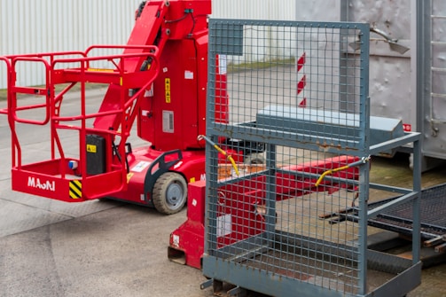 Red articulated boom lift with basket and metal cage