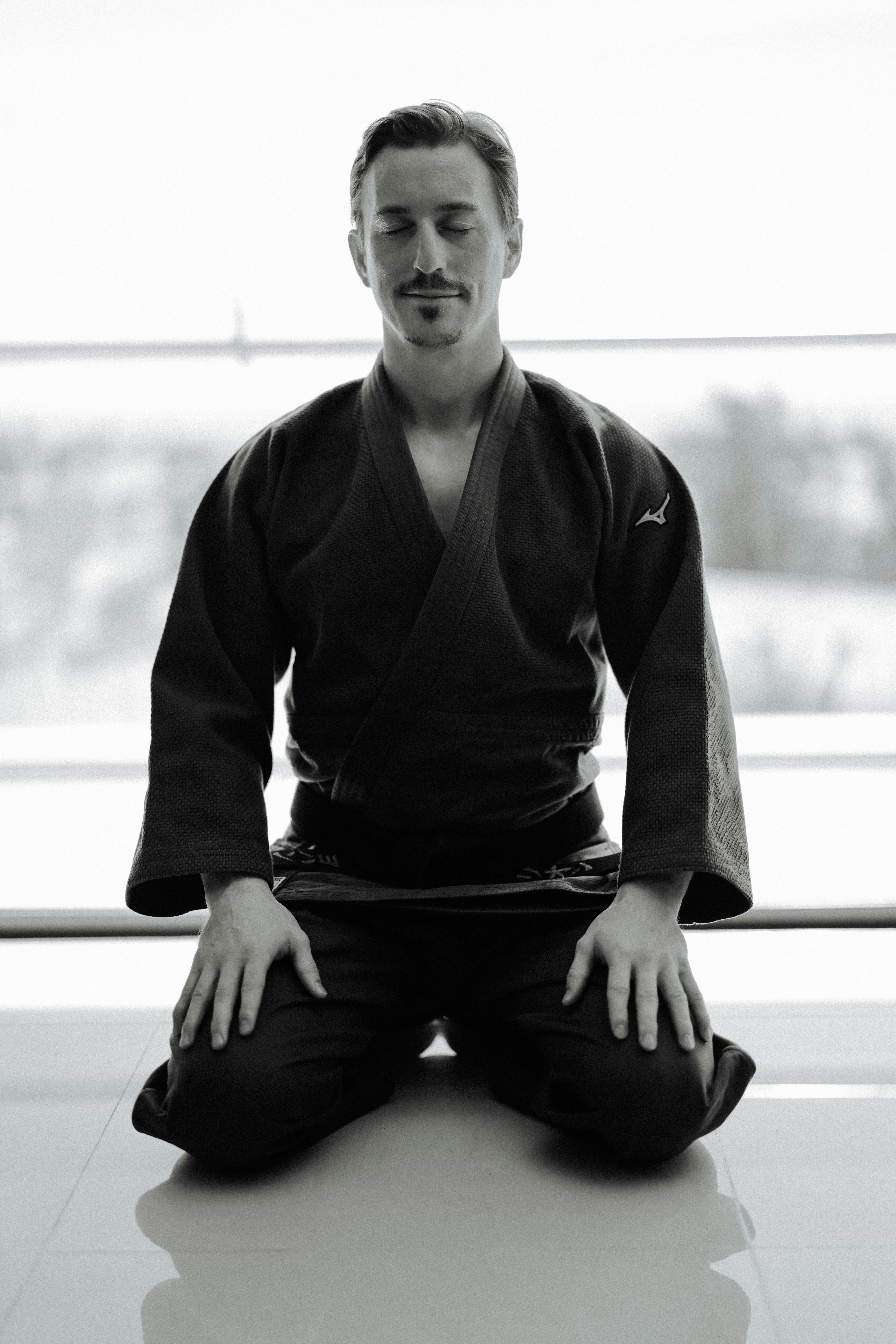 Man in martial arts uniform meditating on knees