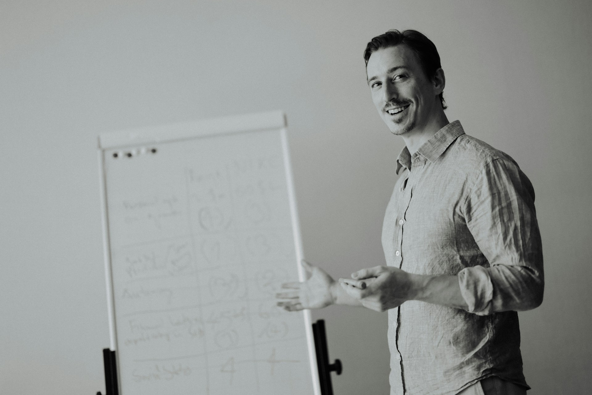 Man presenting by a whiteboard in a studio.