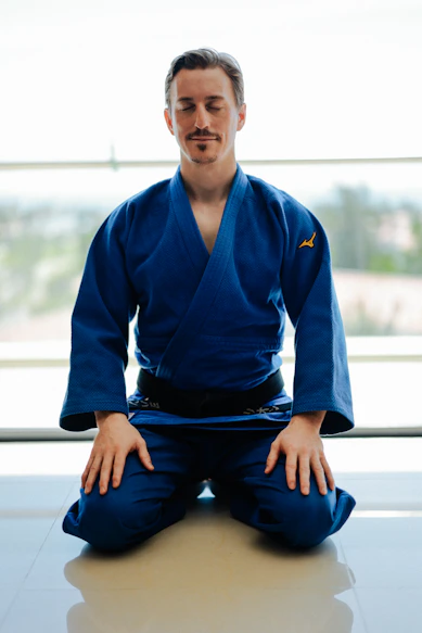 Man in blue judo gi meditating on knees