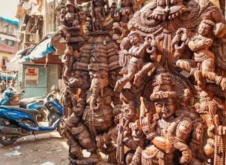 Intricately carved wooden statues of deities displayed outdoors.