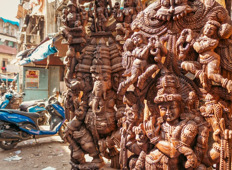 Intricately carved wooden statues of deities displayed outdoors.