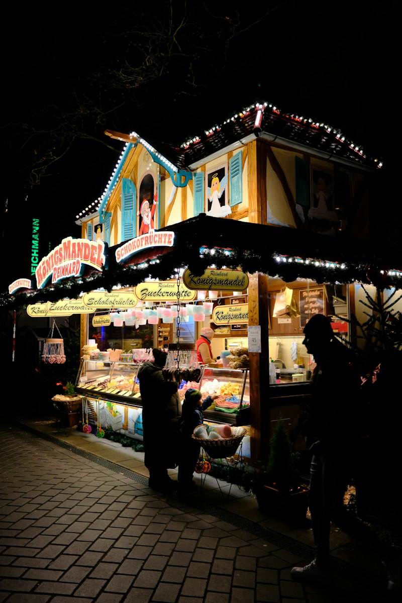 Chalet de marché de Noël illuminé la nuit, entouré de visiteurs