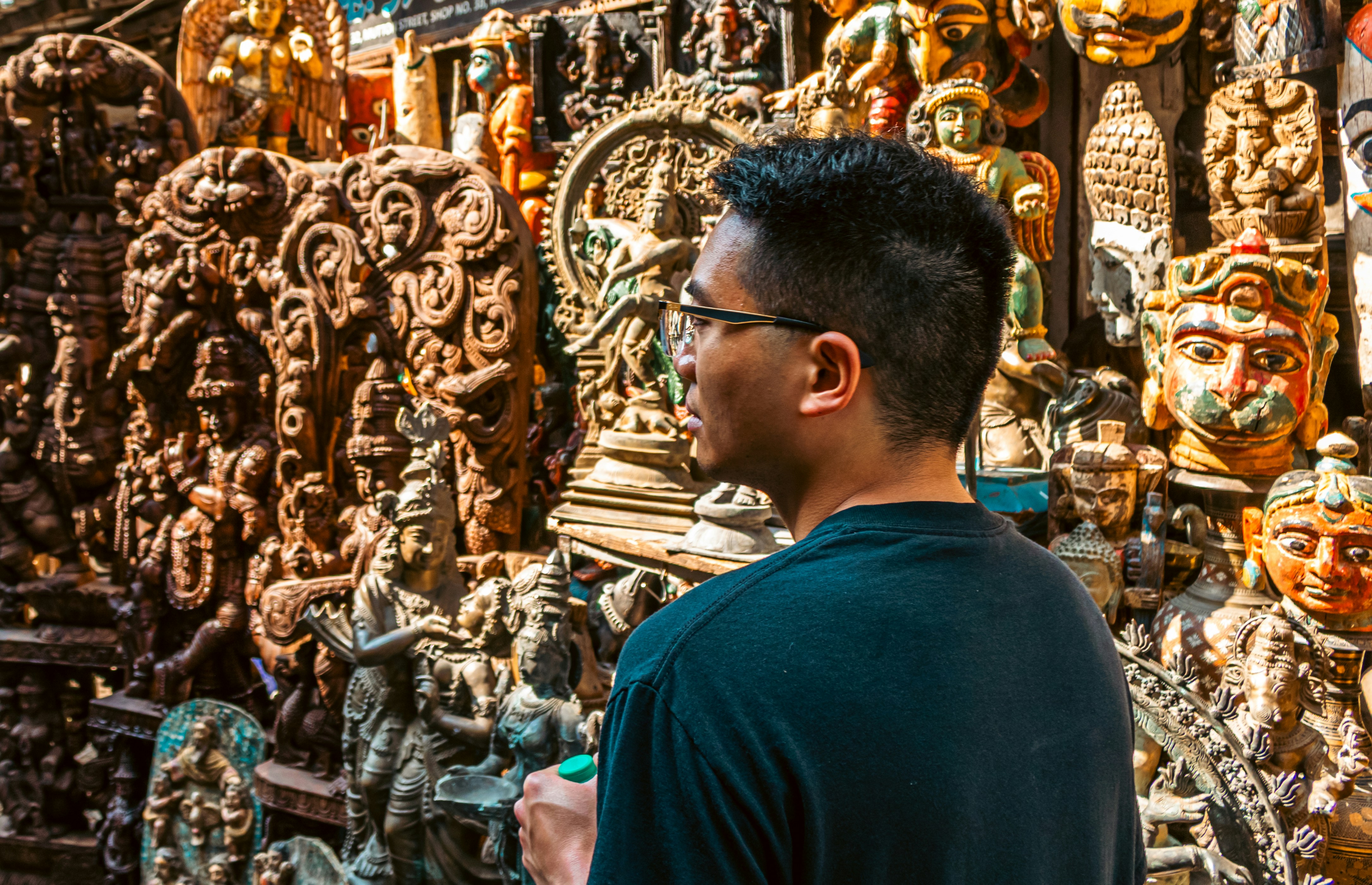 Man looking at collection of carved wooden statues.