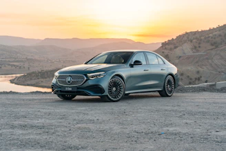 A teal mercedes-benz eqc parked outdoors at sunset