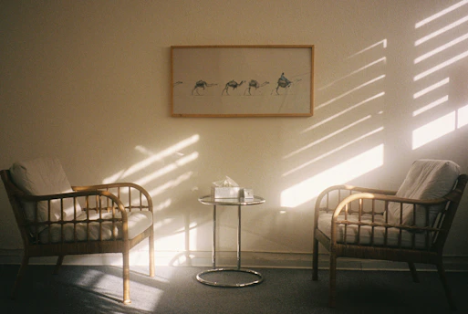 Two chairs and a table with sunlight streaming in.