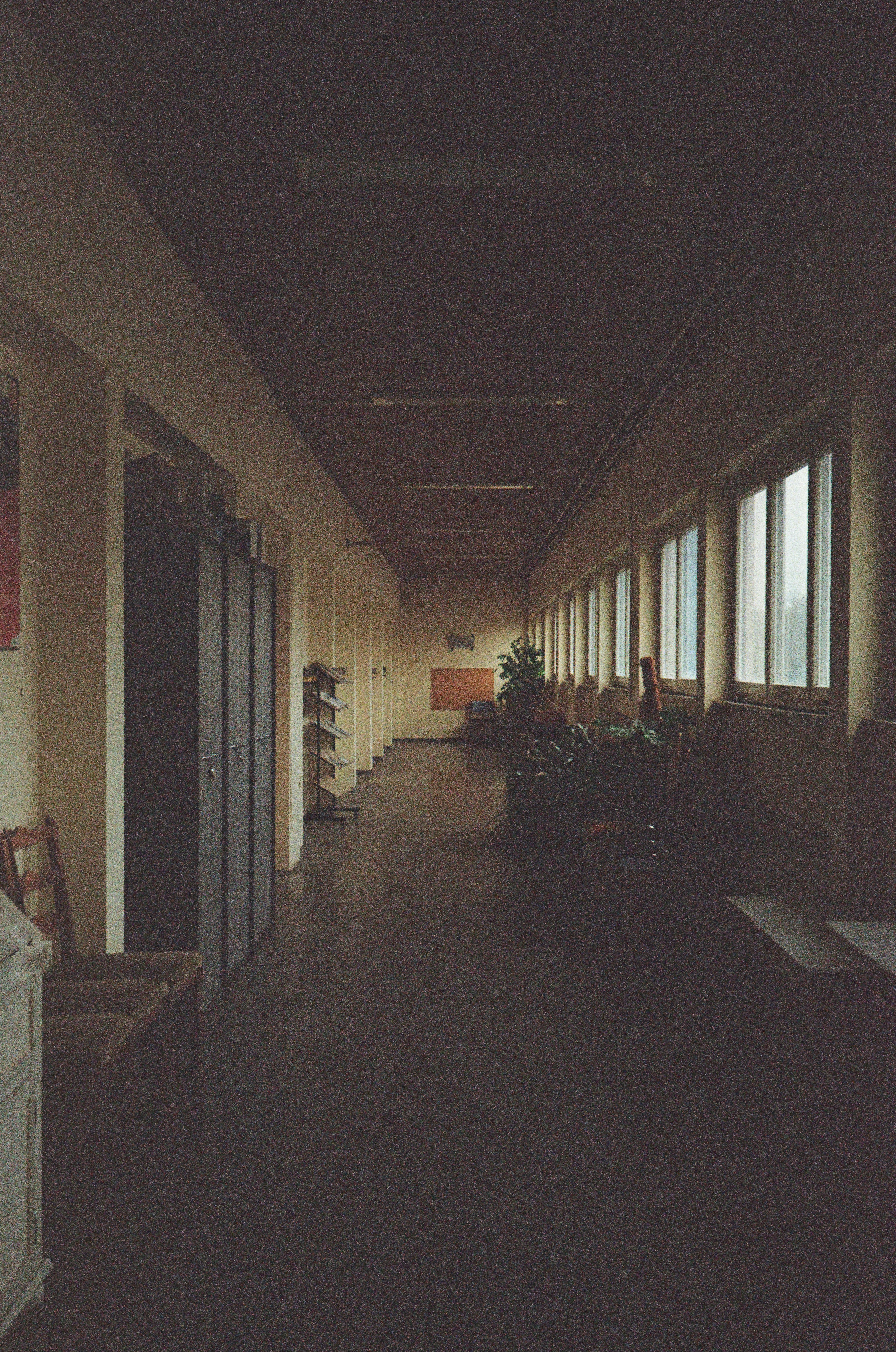 A long, dimly lit hallway with windows on the right.