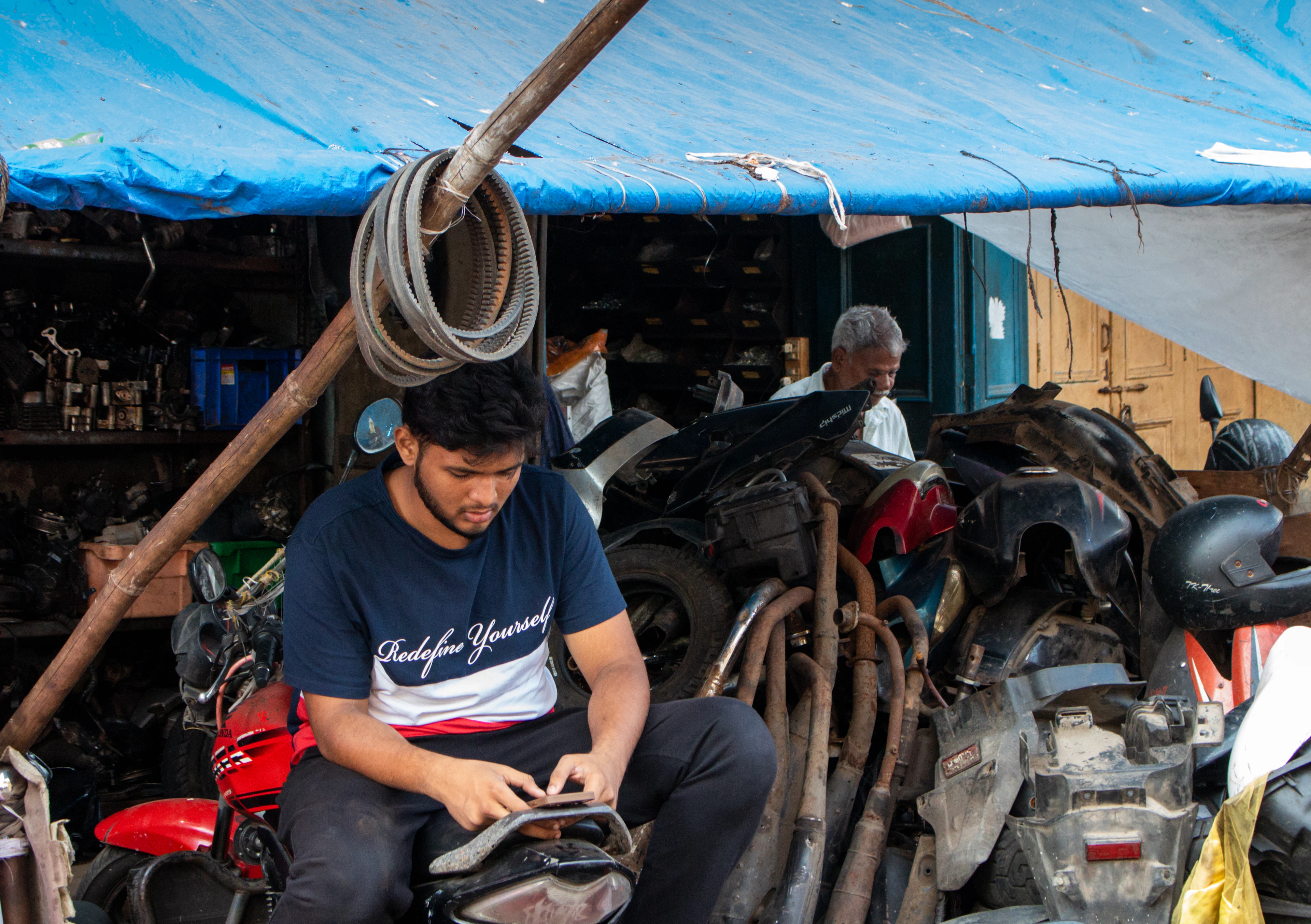 Pemuda di bengkel motosikal menyemak telefon