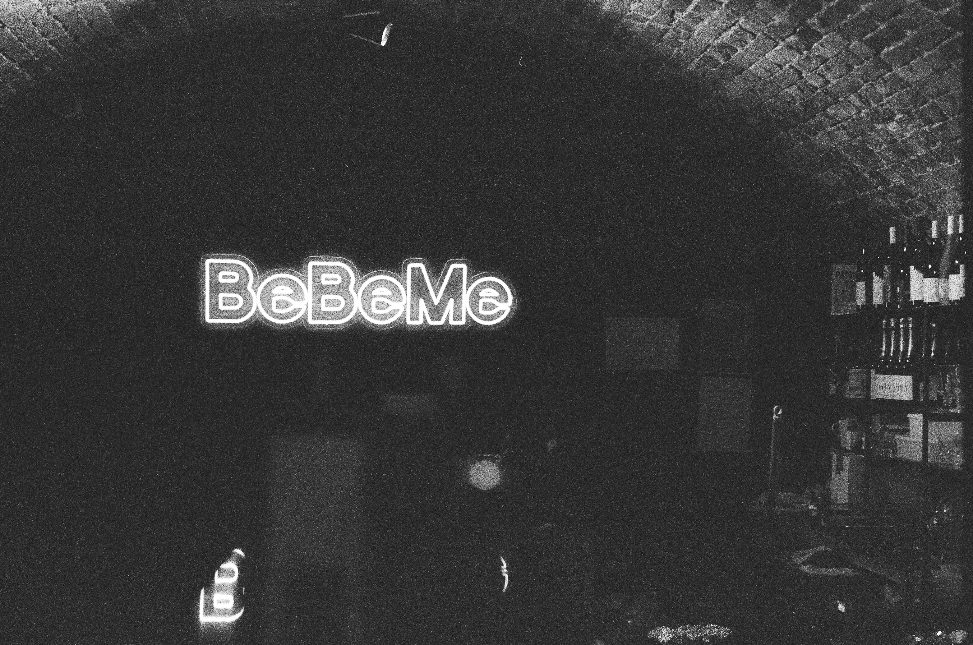 Neon sign reading bcbeme in a dark room.