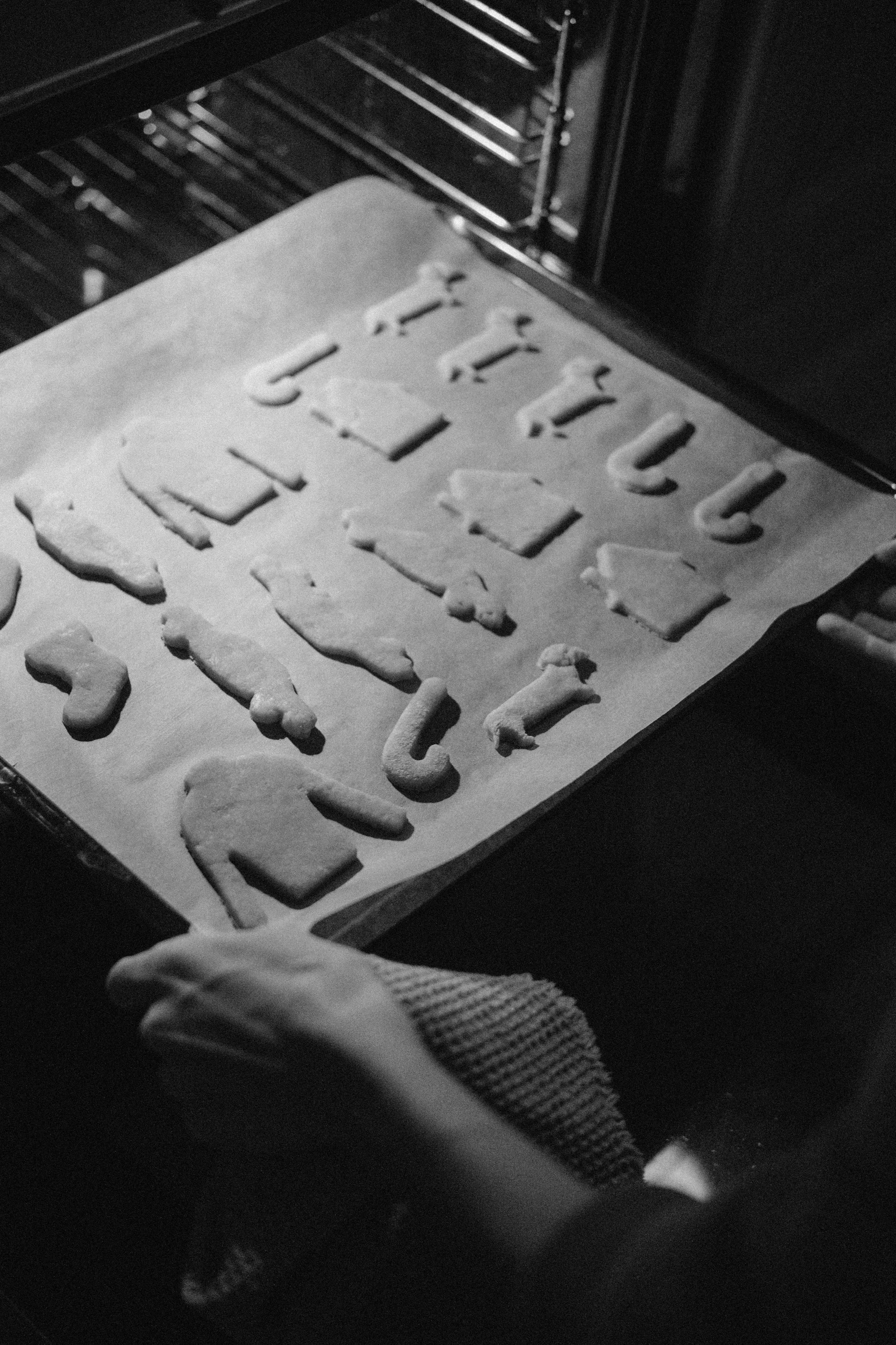 Hands placing a baking sheet into an oven in a home kitchen
