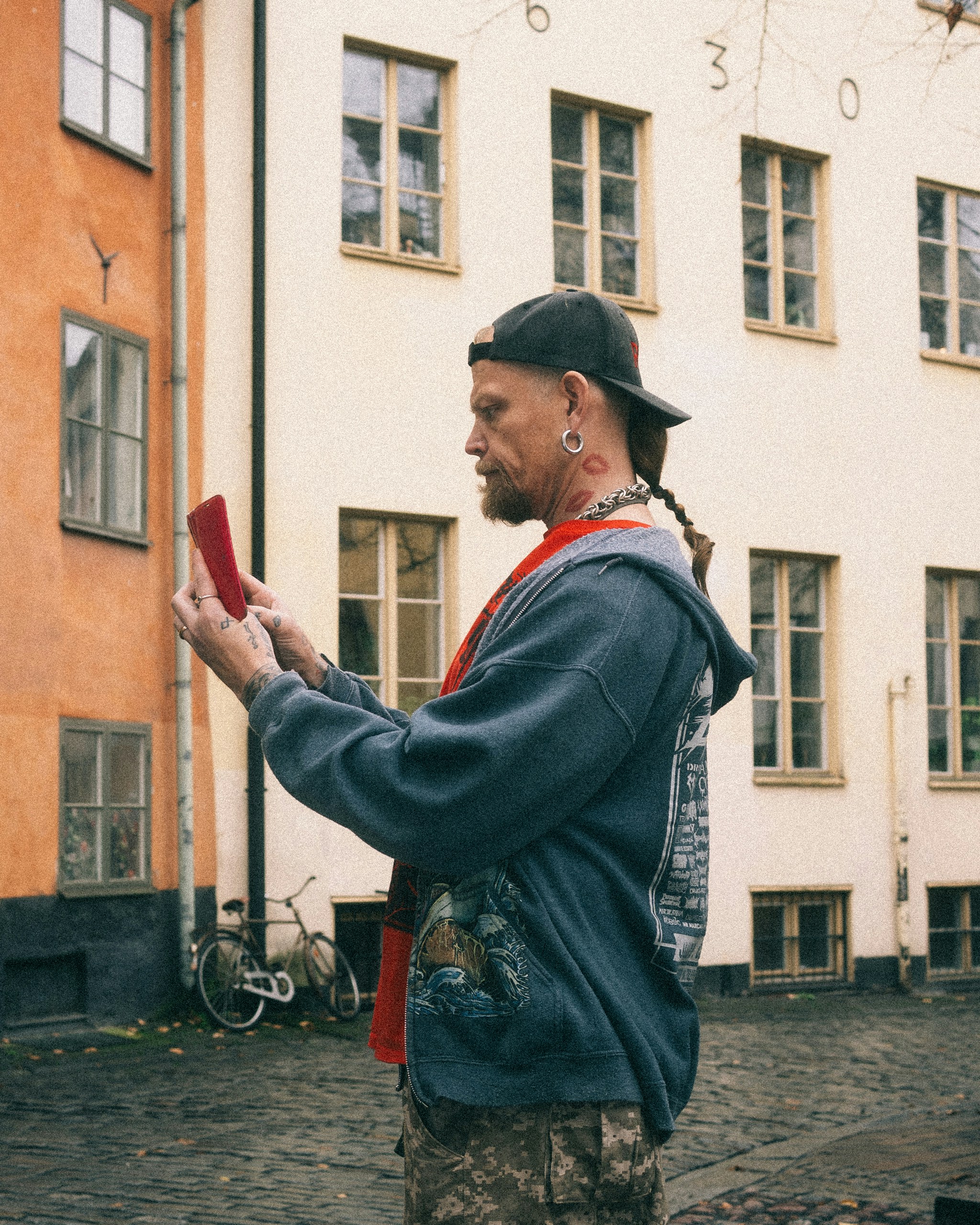 Man in cap looking at red phone in courtyard