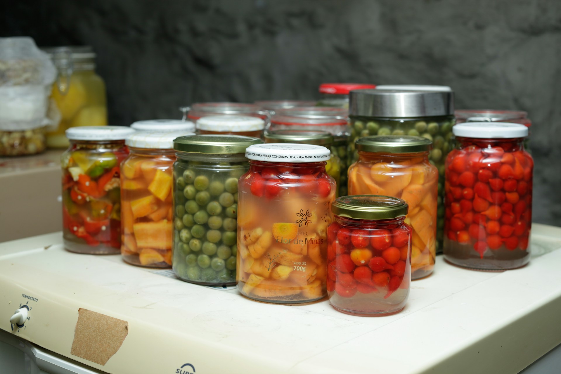 Jars of preserved vegetables and fruits on a shelf.