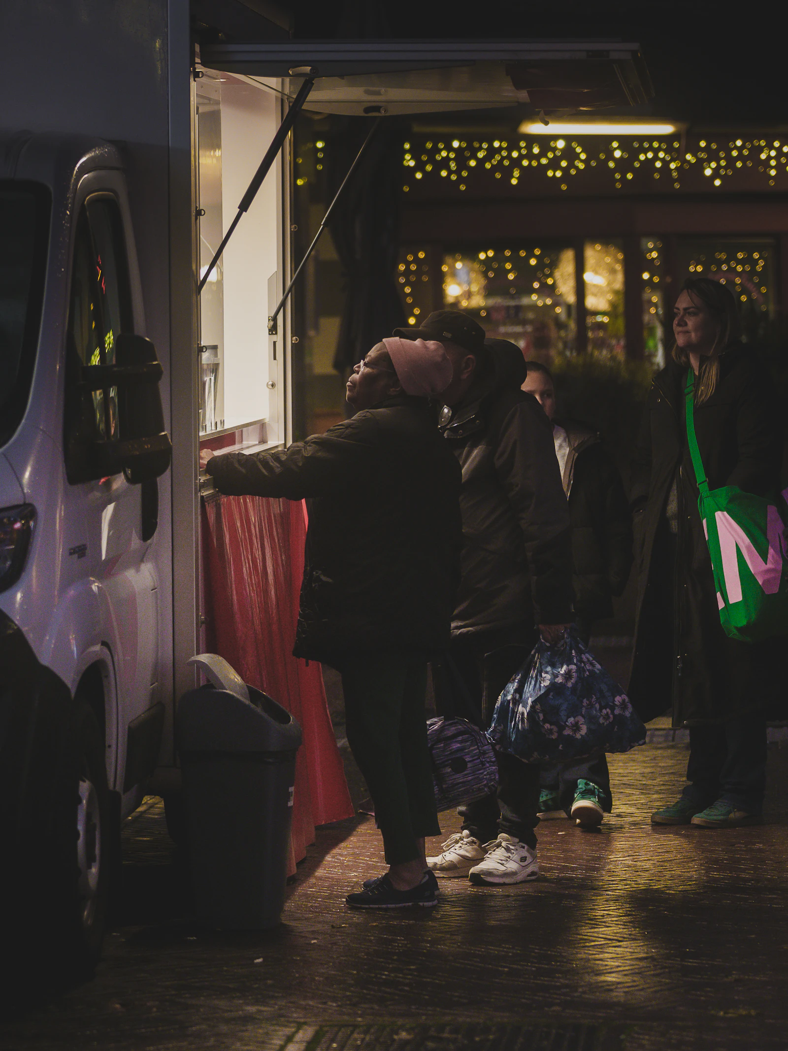 People queuing at a mobile food van at an outdoor night event