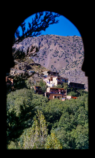 Buildings nestled in a green valley below mountains.