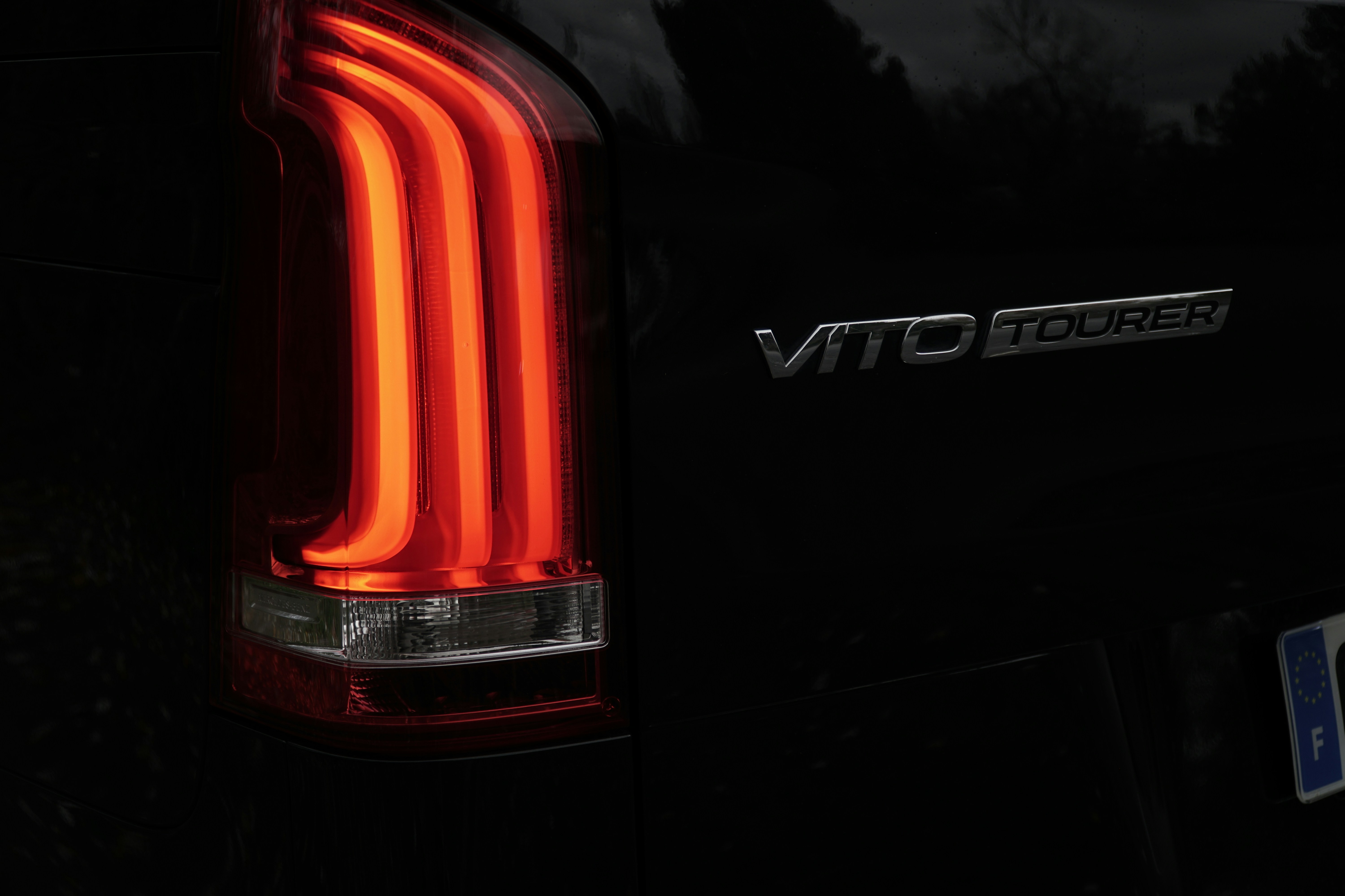 Close-up of a car's illuminated taillight and badge