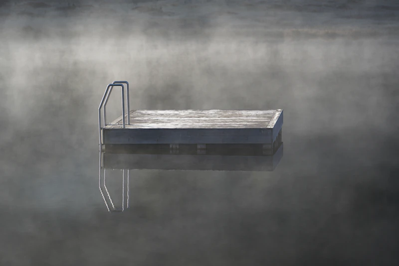 Empty swim dock on a still lake shrouded in morning mist