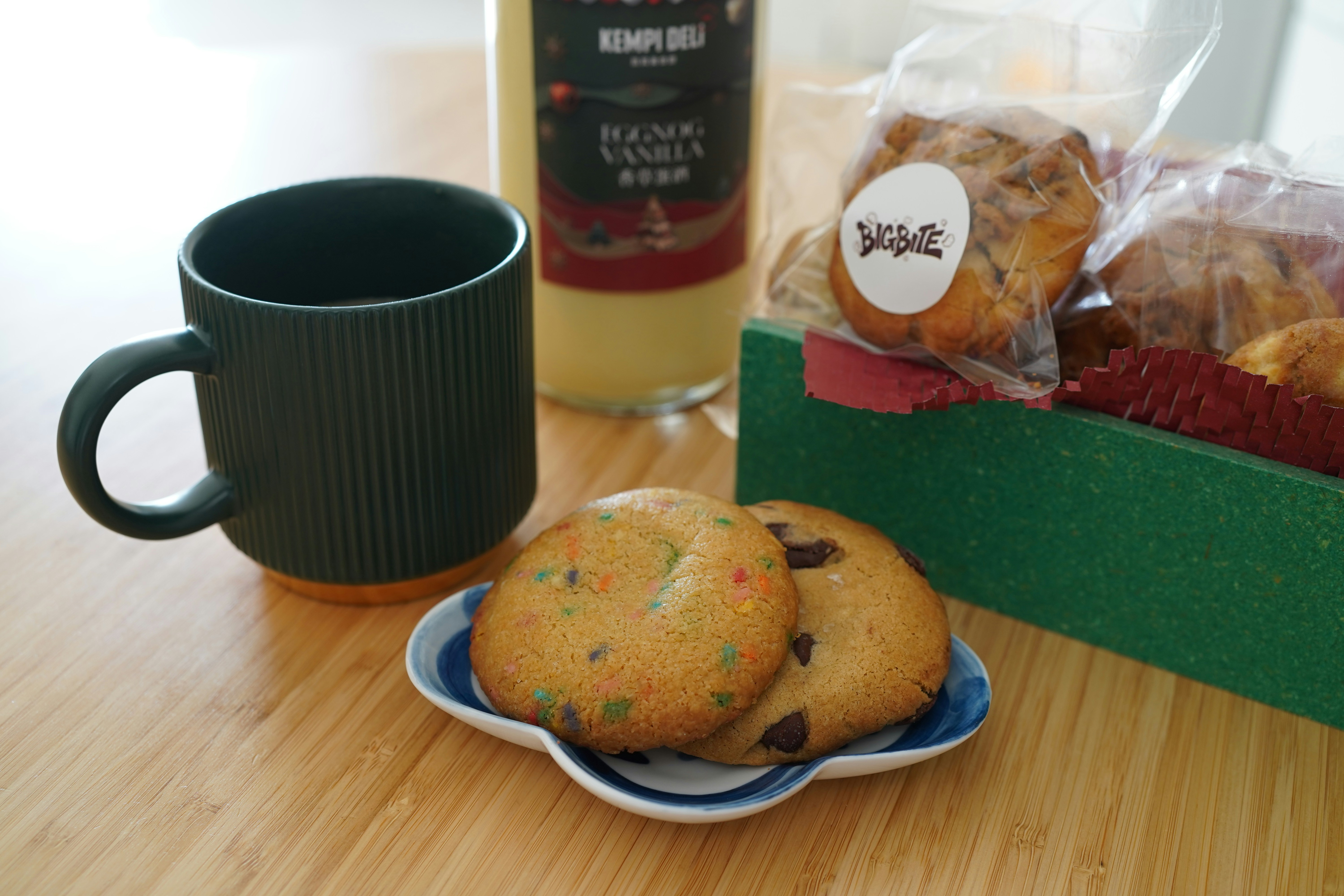 Mug, cookies, and bottled drink on wooden table