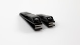 Two black nail clippers on a white background