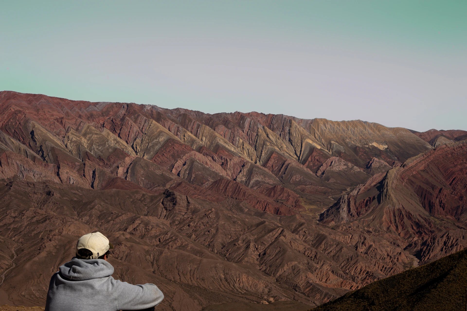 Person looking at colorful mountains under a pale sky