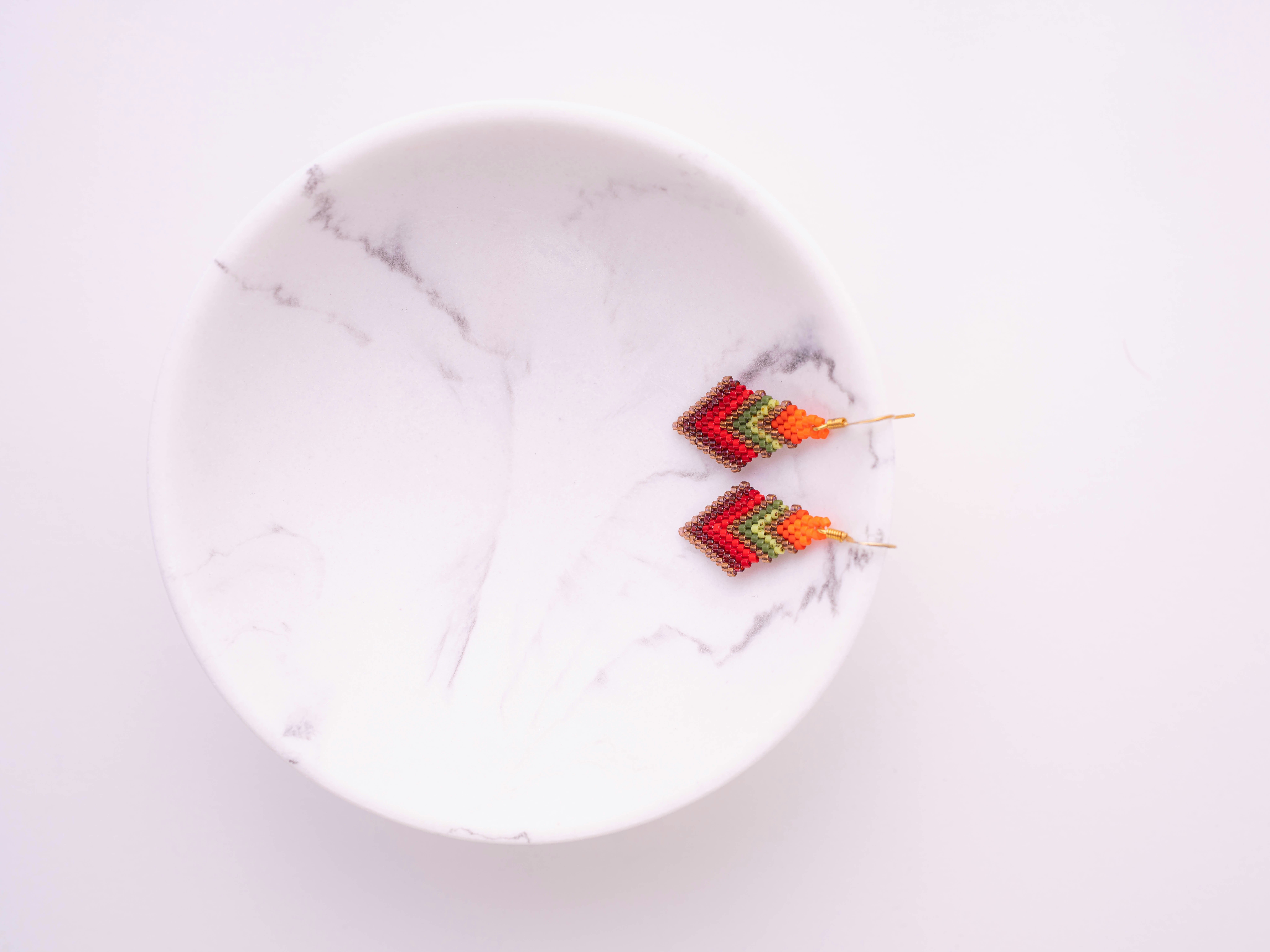 Two colorful chevron earrings on a marble dish.