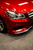 Close-up of a shiny red car's front headlight.
