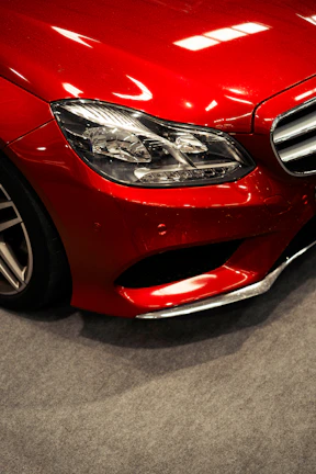 Close-up of a shiny red car's front headlight.