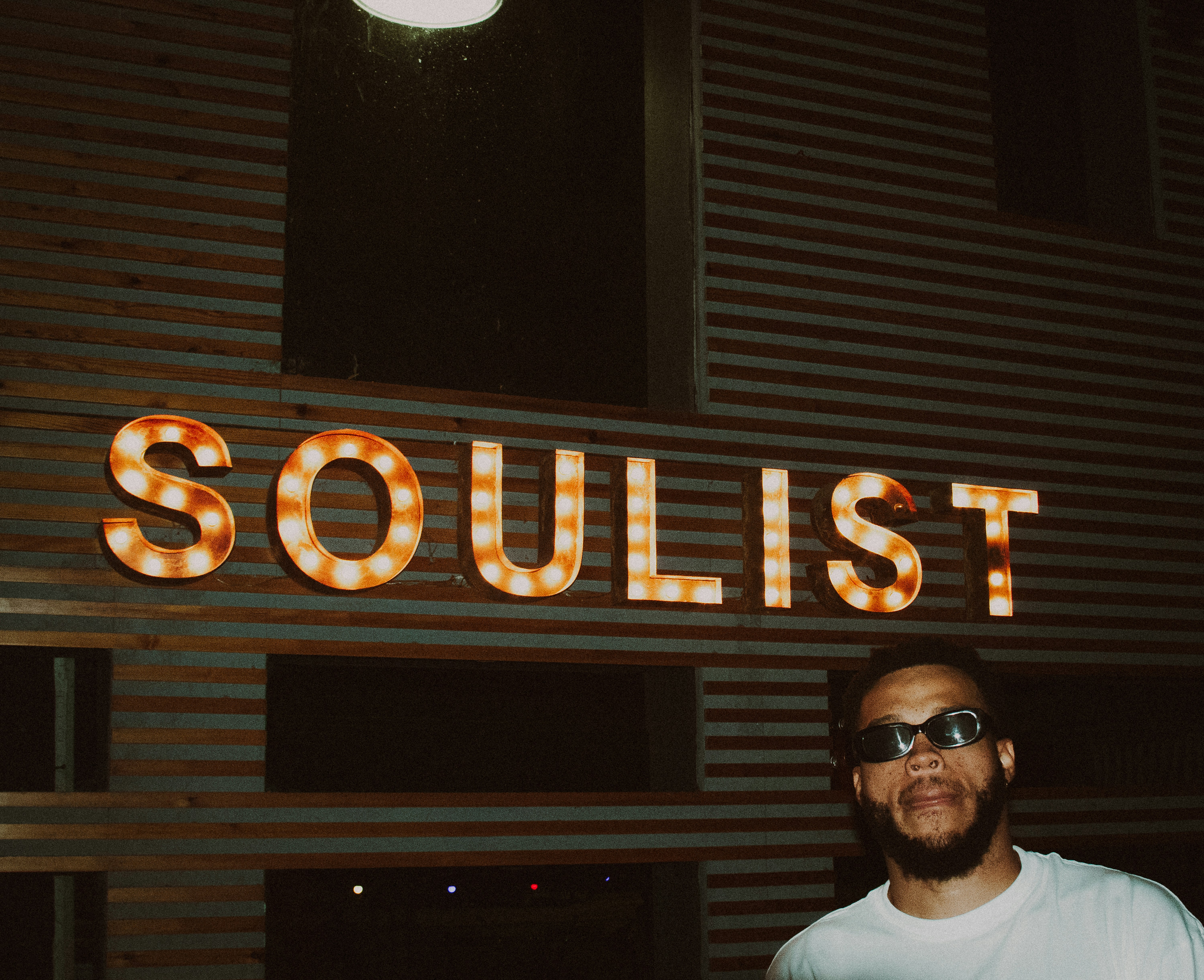 Uomo con gli occhiali da sole in piedi davanti al cartello della Soulist