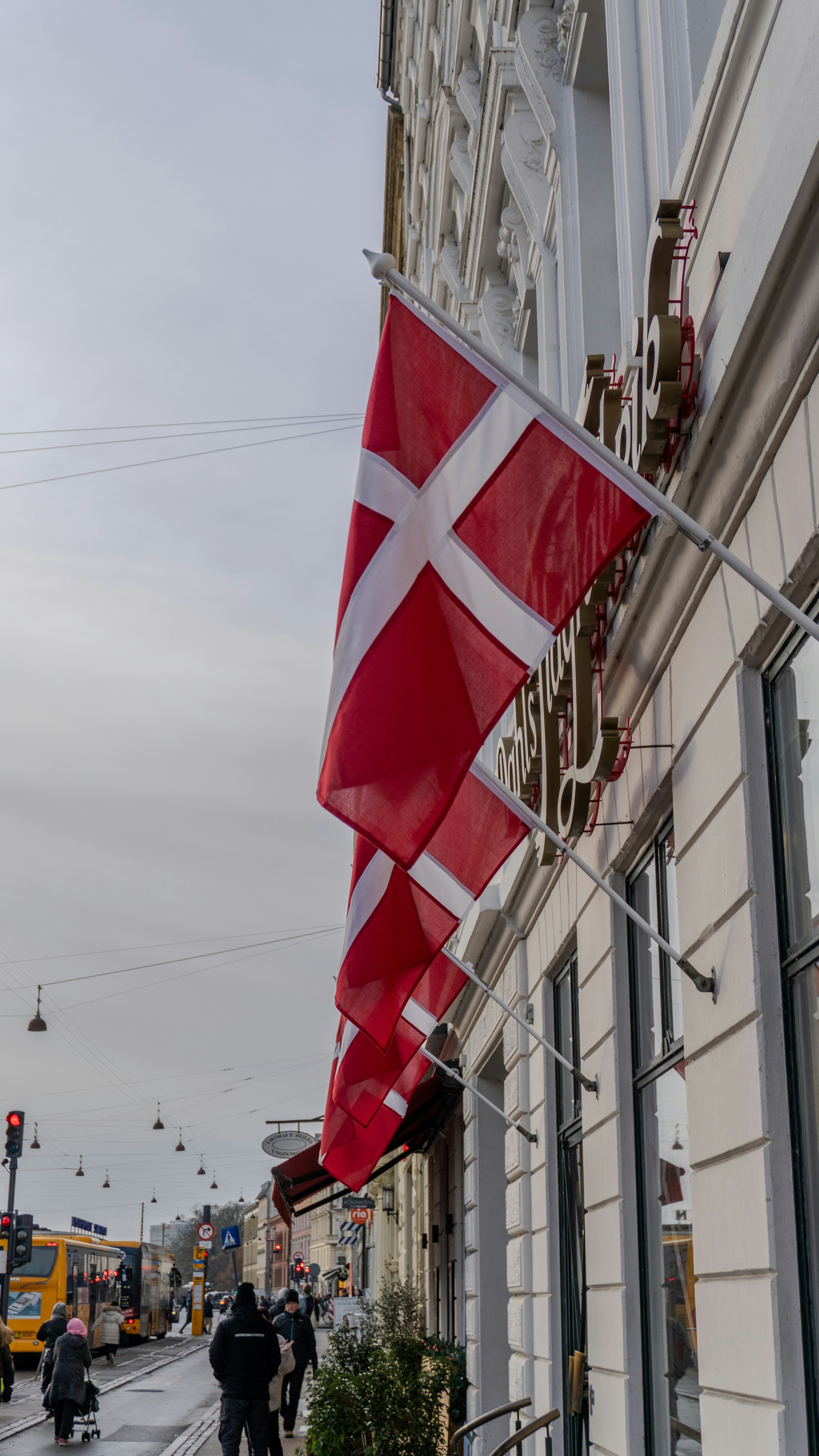 Danish flags hang outside a building on a street.